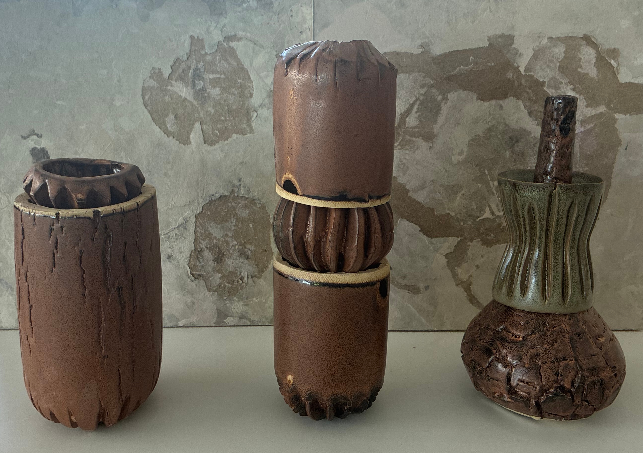 Three arrangements of textured ceramic vessels in brown and green glazes.